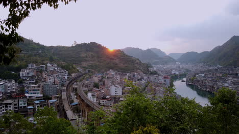 toma panorámica de zhenyuan, guizhou, china con puesta de sol y tren pasando, cámara lenta a alta velocidad