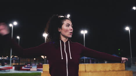 Sportive-Curly-Girl-Stretching-And-Rotating-Arms-In-The-Park-At-Night-4