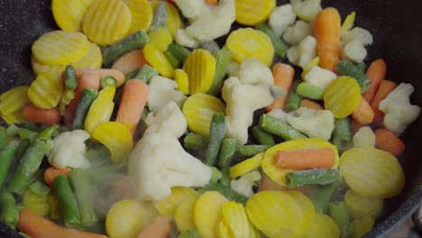 close up view of steaming frying pan and frozen mixed vegetables. vegetarian lifestyle, delicious, being on a diet. healthy food, frying vegetables, organic products