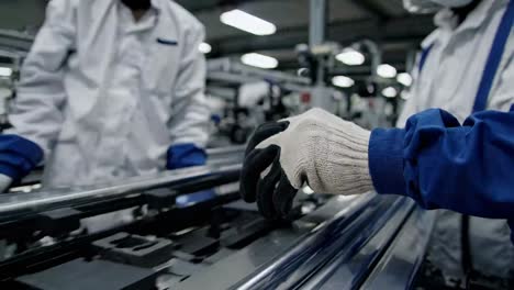 factory worker inspecting metal parts on an assembly line