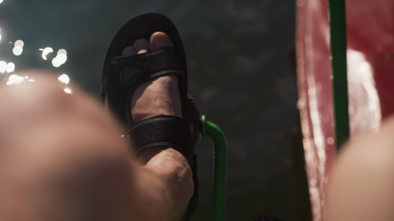 persona adulta pedaleando en un catamarán colorido navegando a lo largo de un río. reflejo de los rayos del sol en el agua fangosa. estilo de vida activo y recreación en la naturaleza