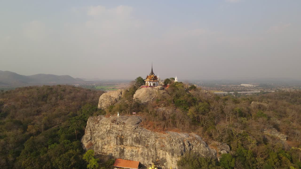 toma cinematográfica aérea del carro del templo budista wat phra phutthachai ubicado en la cima de la montaña al rock que sobresale del denso bosque tropical, en saraburi, tailandia