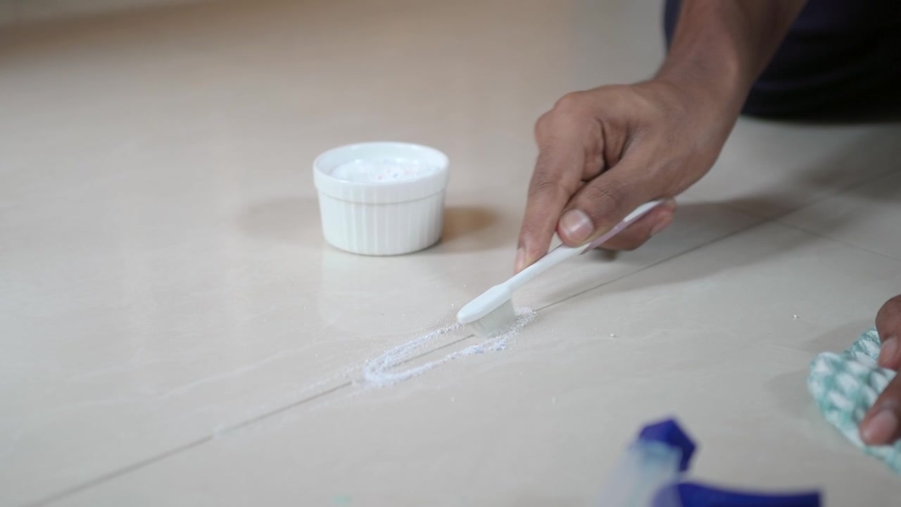 Close-up of Hand Cleaning Tile Grout with a Toothbrush