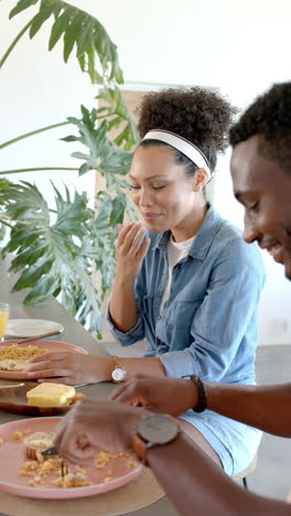 vertical video: eating breakfast together, couple enjoying meal and laughing at home table