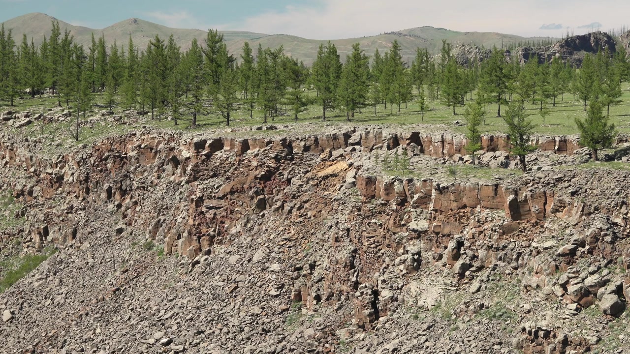 Kallioinen jyrkänne, josta avautuu näkymä metsäiseen laaksoon Mongoliassa