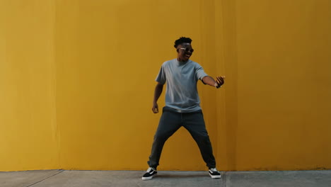 energetic man dancing in front of a bright yellow wall