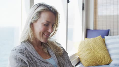 Smiling-caucasian-mature-woman-sitting-and-taking-away-hairs-in-sunny-living-room