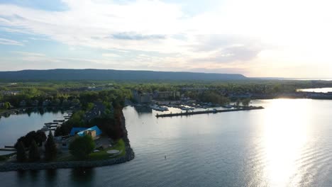 drone flying around houses nestled on a lake ontario peninsula in collingwood at sunrise