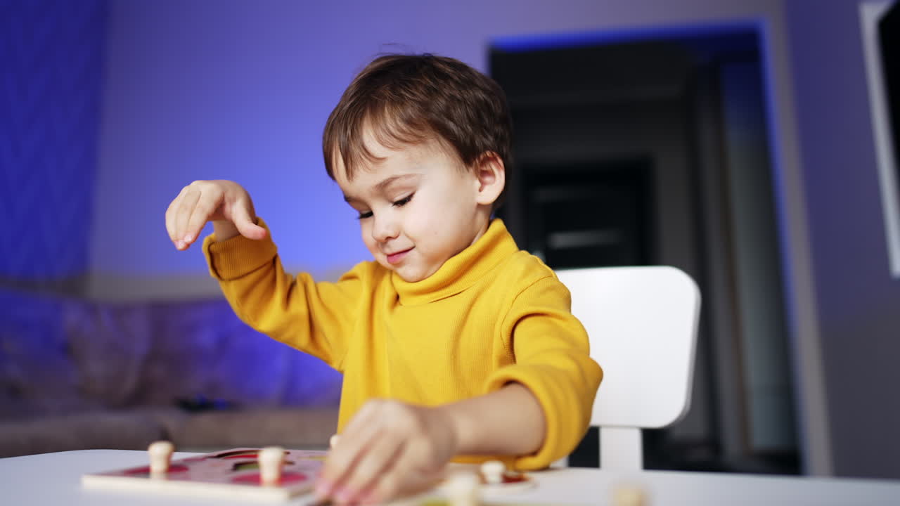 Cute little toddler plays sitting at his desk at home. Adorable two year old boy matching puzzles.