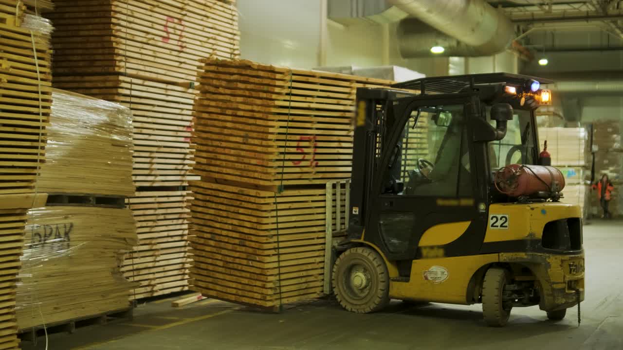 Gabelstapler hebt Stapel von Holzbrettern in einem Lager.