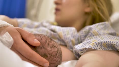 newborn baby being gently held by the mother during their first feed in a hospital bed, symbolizing the bond between mother and child