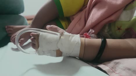 Close-Up-Shot-Of-IV-Infusion-ON-Bandaged-Hand-Laying-On-Bed