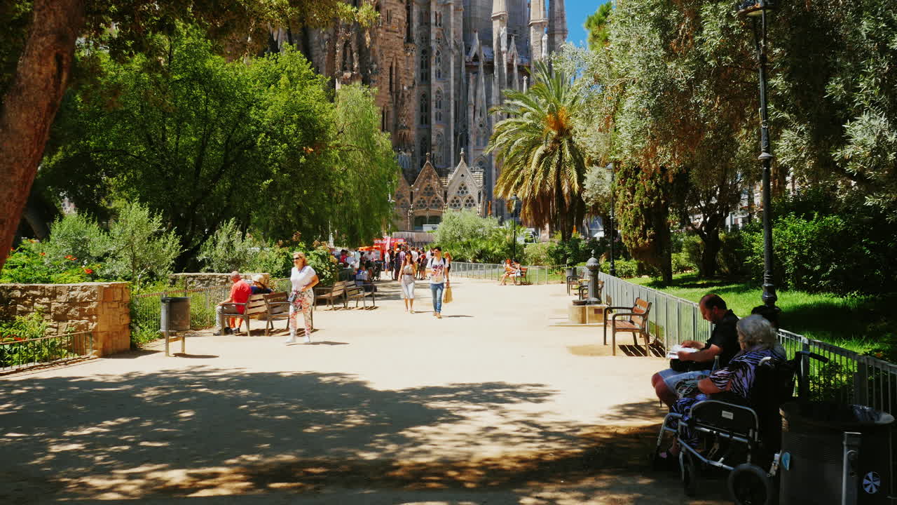 La célèbre église de la Sagrada Familia à Barcelone. Des touristes marchent et la caméra se dirige vers le temple.