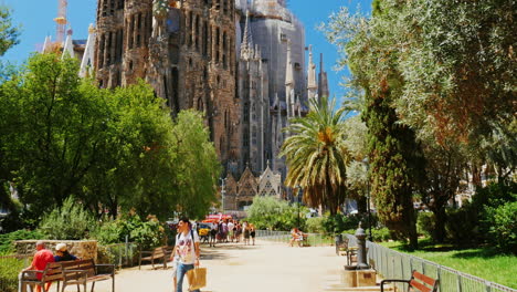 the famous sagrada familia church in barcelona tourists walking the camera moves toward the temple