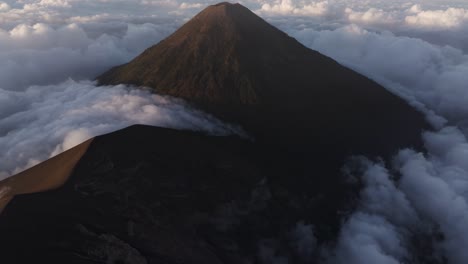 reveal shot of fuego volcano surrounded by morning clouds, aerial