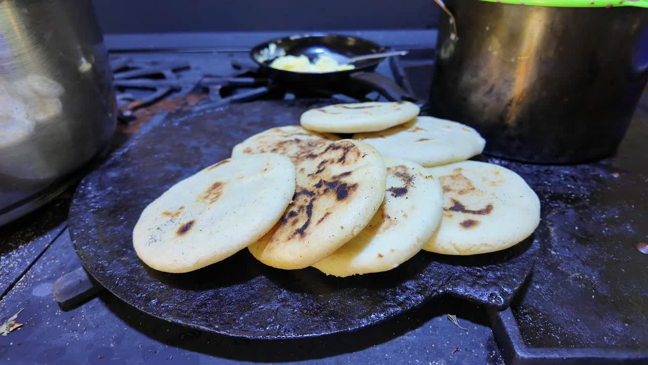 Freshly made arepas cooking on a traditional cast-iron budare, crispy and golden
