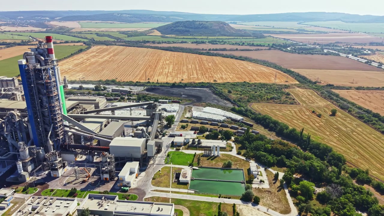 Cement factory near fields with machinery and green areas in the countryside on a clear day