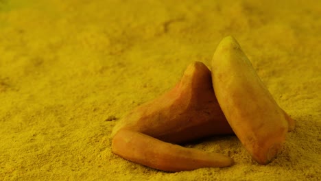 disparo giratorio de tres patatas dulces colocadas en un lecho de especias en polvo amarillo
