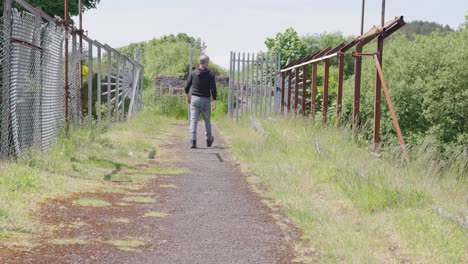 apocalyptic scenery, lonely man walking, dilapidated structure, slow-mo