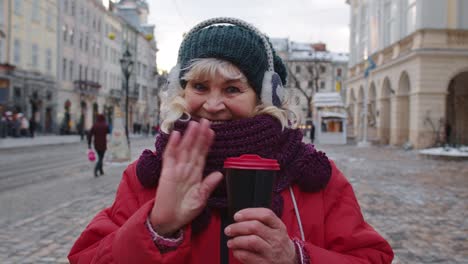 Senior-woman-grandmother-tourist-smiling,-showing-thumb-up-in-winter-city-center-of-Lviv,-Ukraine