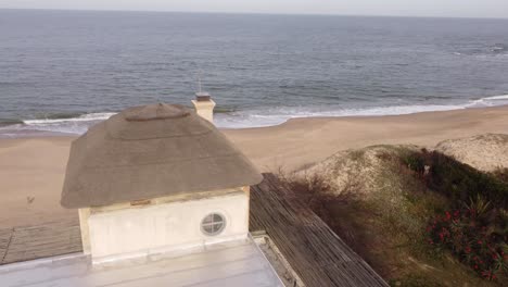 Vista-Aérea-De-La-Casa-Frente-A-La-Playa-De-Jose-Ignacio-Durante-El-Día-Soleado,-4k