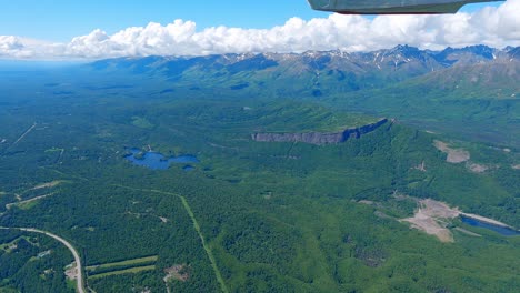 pequeño avión que volaba sobre el río matanuska cerca de la ciudad de palmer con la cordillera talkeetna de alaska en la distancia