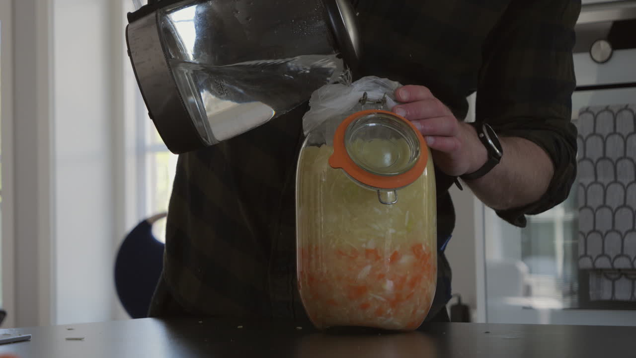 persona creando un bloqueo de agua o bloqueo de fermentación para frasco con chucrut o kimchi, cierre