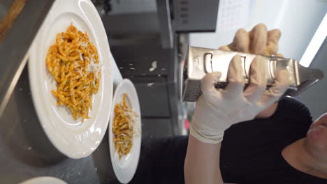 chef grating parmesan cheese over trofie pasta dishes with tomato sauce in slow motion