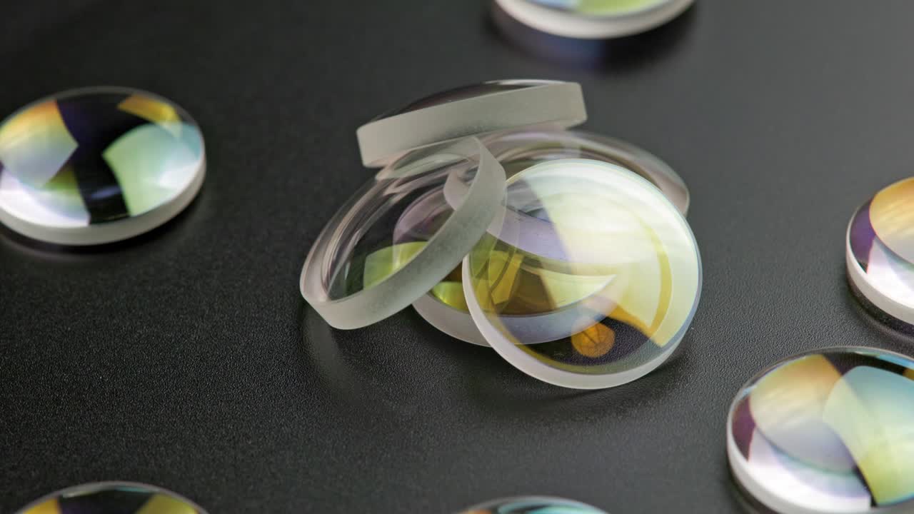 fondo giratorio en bucle de cuadro completo de una pequeña pila de piezas de lente redondas convergentes en una superficie negra plana