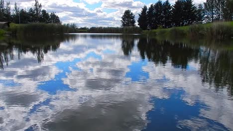 Blue-vibrant-lake-water-mirror-reflection-bright-scenic-cloudy-sky