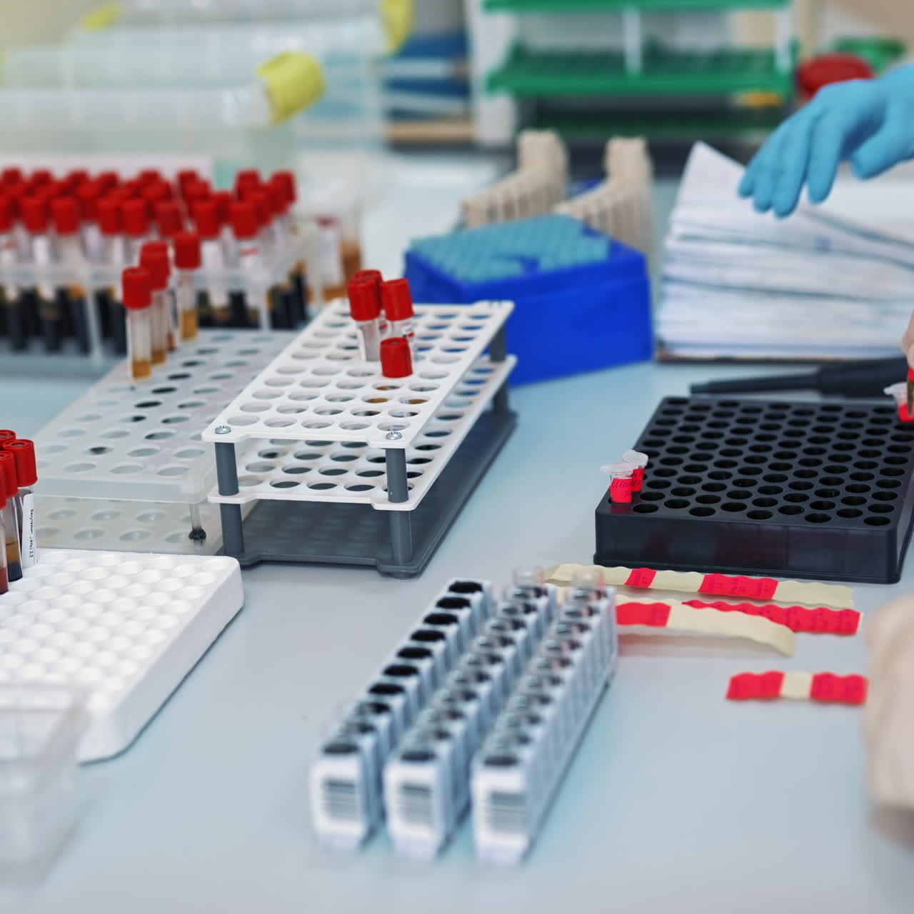 Professional laboratory workers pouring blood samples into vials on the table. Medical laboratory technicians making blood experiments in research clinic.