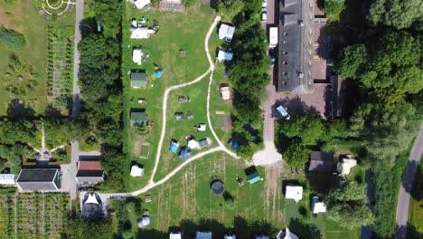 Top-down-aerial-view-of-vehicle-towing-caravan-entering-a-camping-site