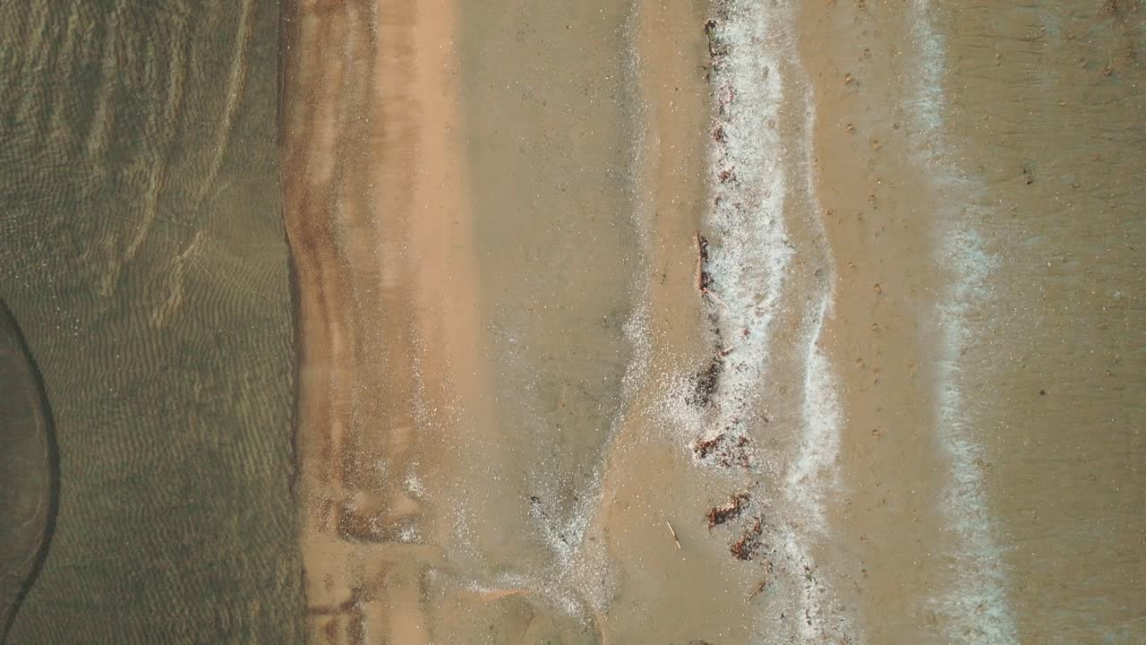 la puesta de sol dorada sobre el lago huron con las olas golpeando suavemente la orilla arenosa