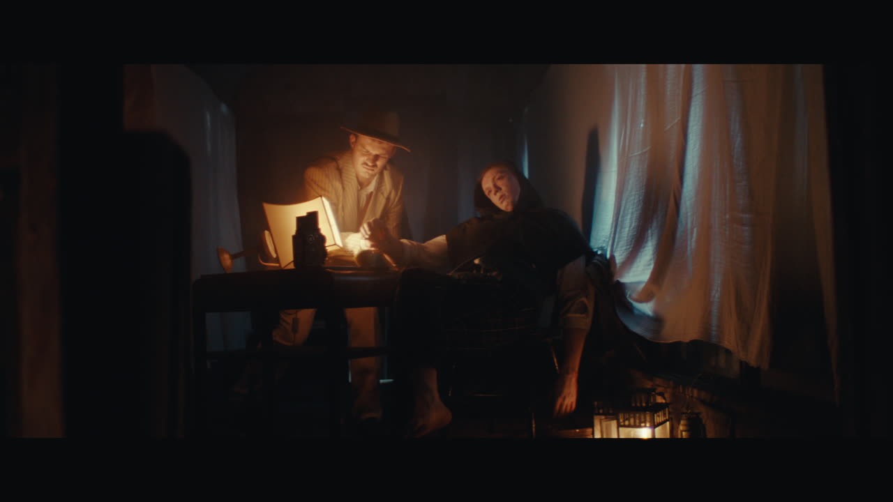 A man in hat arranges dead perfomancer body inside the circus cart