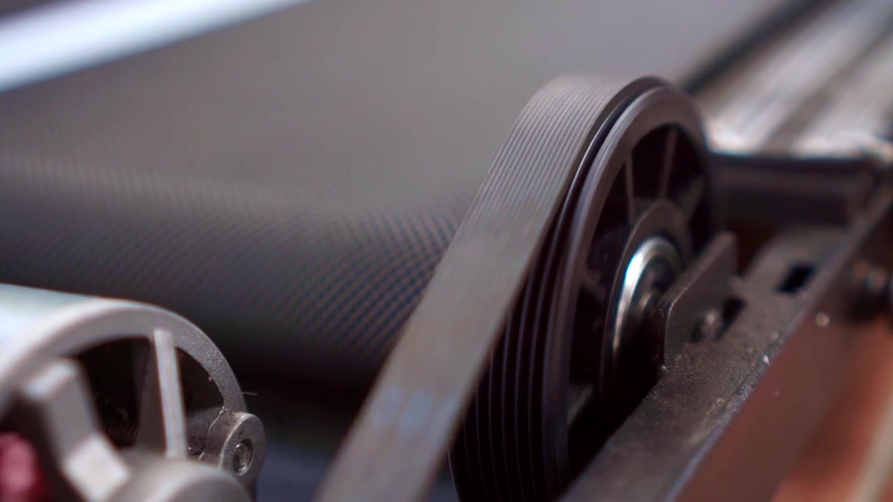 Industrial belt drive system with spinning pulley wheels, close up view, mechanical machine parts, engineering technology footage scene.