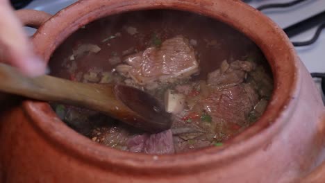 Gemüse-Und-Fleisch-Im-Tontopf-Mit-Holzlöffel-Würzen