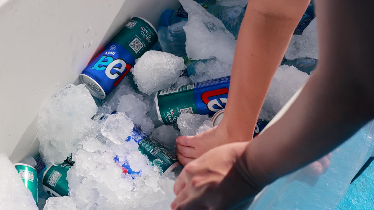 Hands reach into an ice-filled cooler on a boat in Phuket, selecting drinks under bright, natural lighting