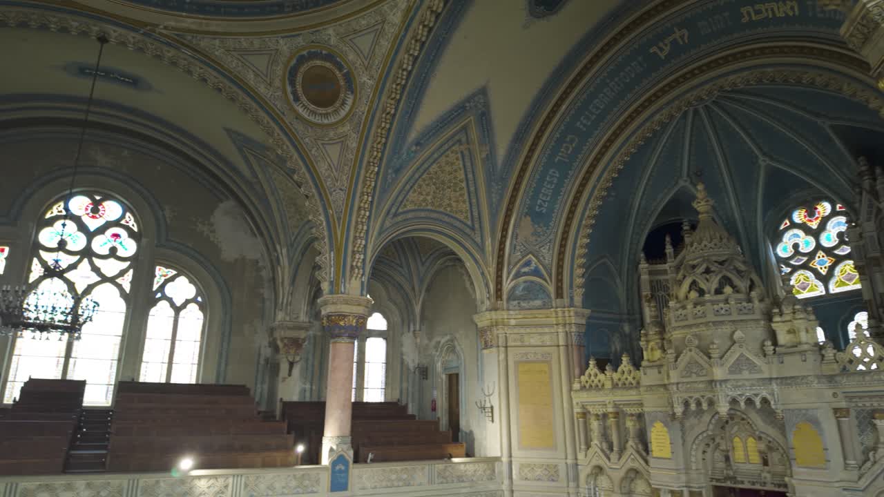 Smooth pan across the seating area and altar on the first floor inside Szeged Synagogue, highlighting ornate architecture and religious details