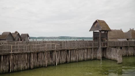 Reetdachkonstruktionen-Auf-Stelzen-über-Dem-Wasser,-Die-An-Prähistorische-Behausungen-Erinnern,-Bewölkter-Tag