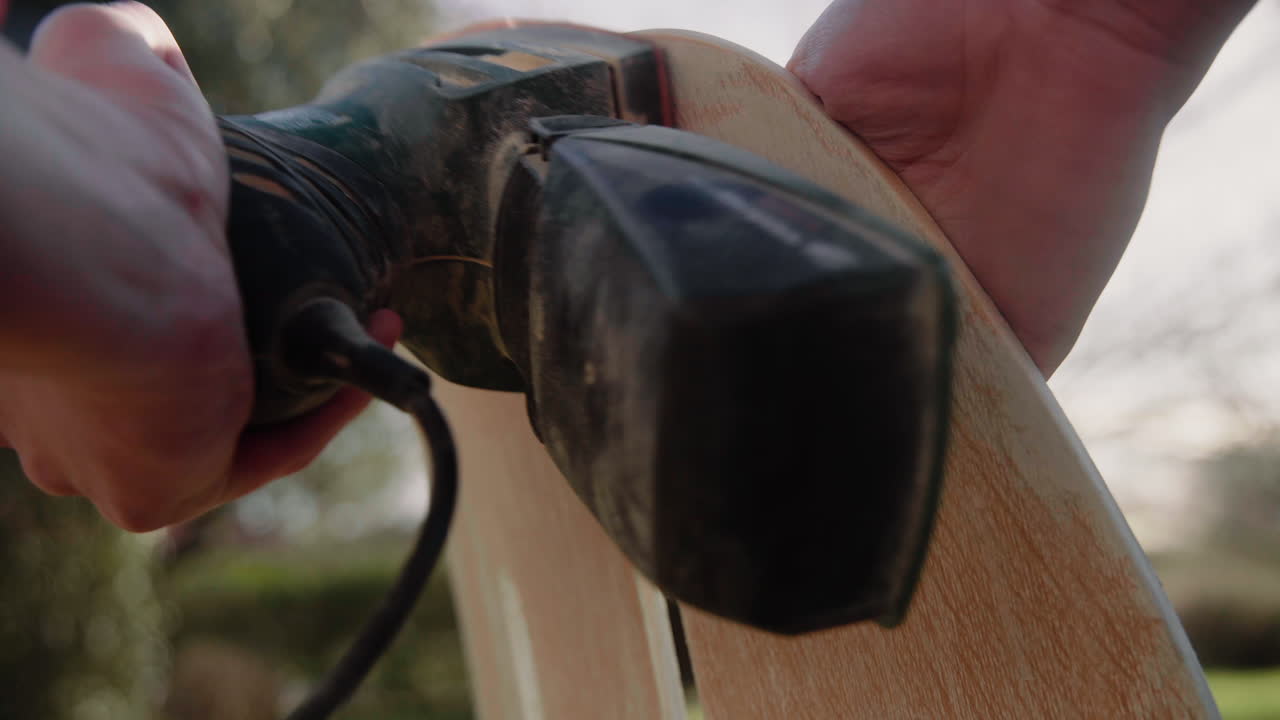 Detail Shot of hands of a Handyman Using Polishing Machine To Polish Wood and refurbish an old vintage design chair in the garden on a sunny day 4K