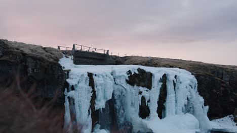 cascada de kirkjufellsfoss congelada durante la hora dorada cielo vibrante, islandia