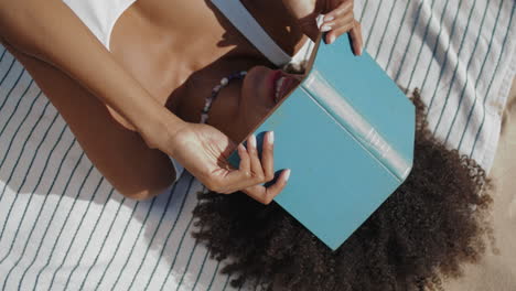 girl hiding face book resting on beach closeup. vertical playful shore woman