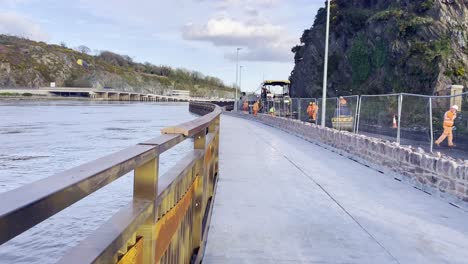 Finishing-of-the-Waterford-greenway,-workmen-laying-tarmac,-the-Suir-river-on-the-left-and-Waterford-railway-station