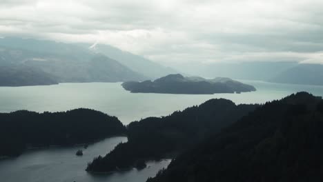 Calm-Lake-And-Mountains-In-Fog-In-The-Countryside-Of-British-Columbia,-Canada-At-Sunrise