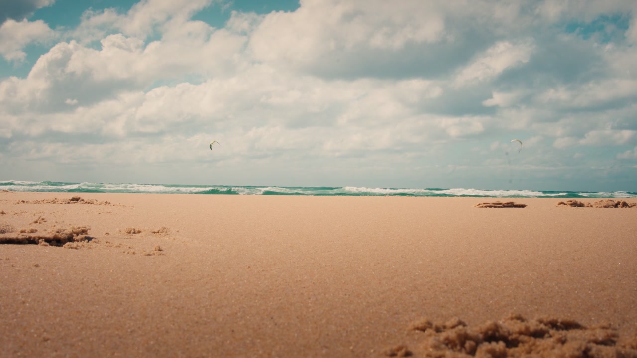 Plage de la Salie præsenterer et stort og tomt sandlandskab, der strækker sig mod Atlanterhavet. Bredt udsyn i øjenhøjde over kystens vildmark under en blød blå himmel og et mildt lys.