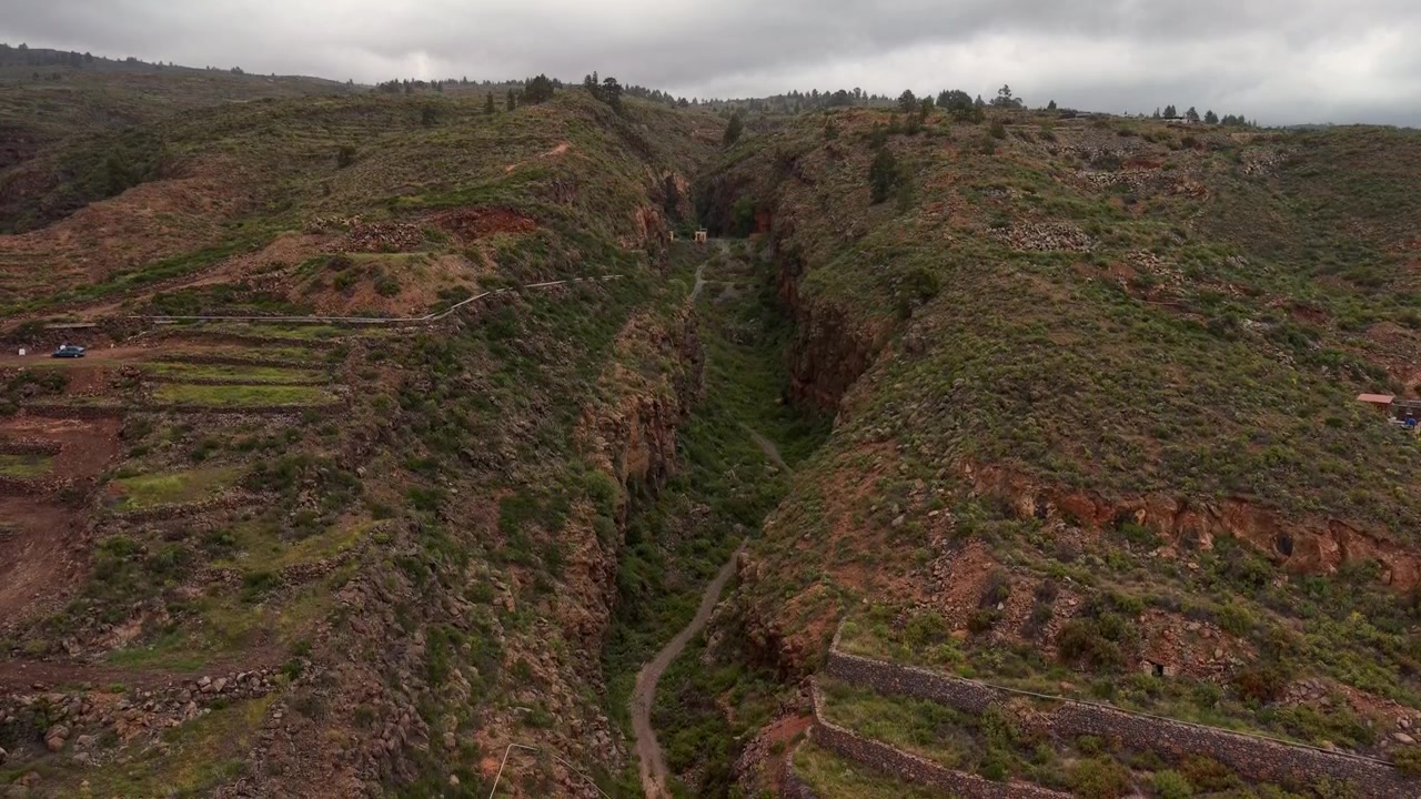 Vista aerea di un profondo burrone e colline vulcaniche terrazzate sotto cieli nuvolosi a Tenerife