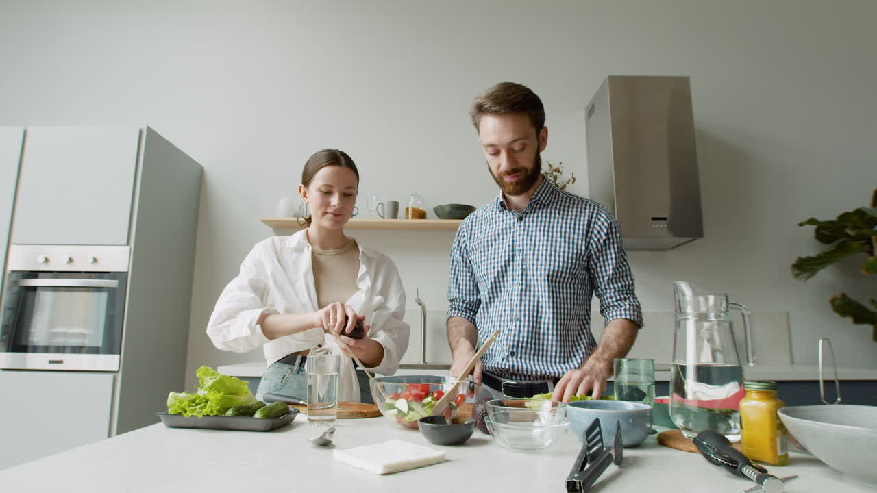 alegre pareja joven preparando ensalada juntos en una cocina moderna 1