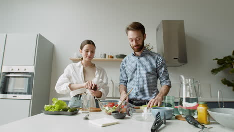 cheerful young couple preparing salad together in a modern kitchen 1