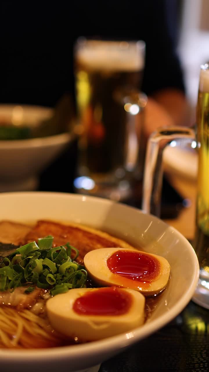 Two people sharing ramen and beer at a table