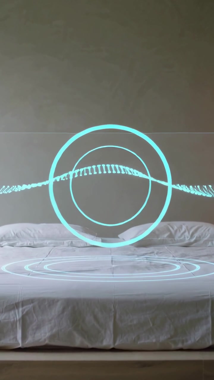 Vertical video: Animating turquoise hologram above bed with sheets in bedroom showing rings on play